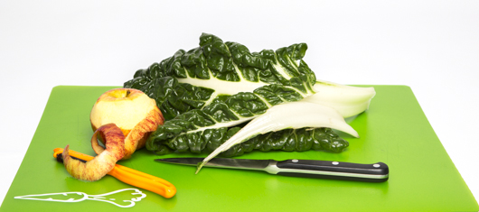 Raw silverbeet with stem partially removed, apple partly peeled, a knife