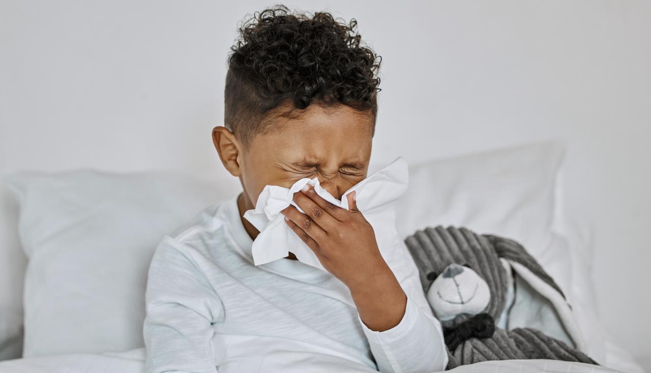 Photo of a child blowing their nose in bed 