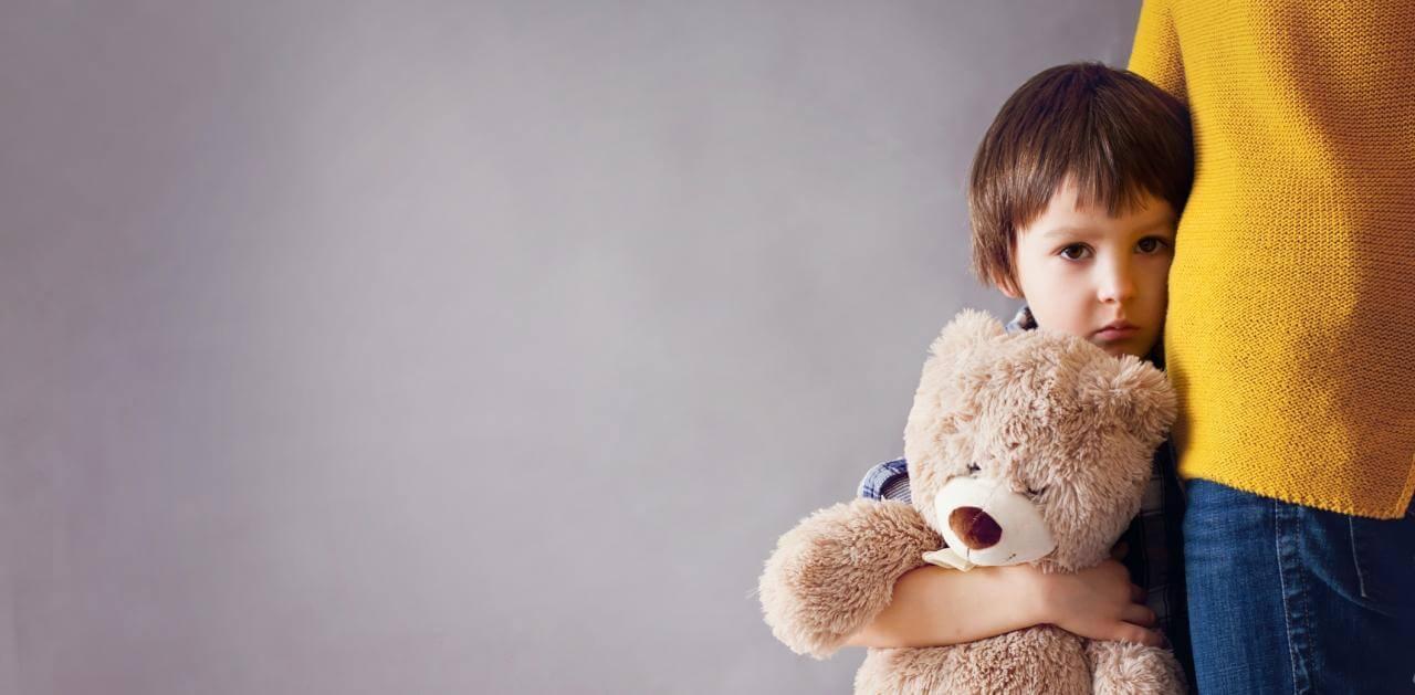 Photo of sad boy hugging his mother and his teddy bear