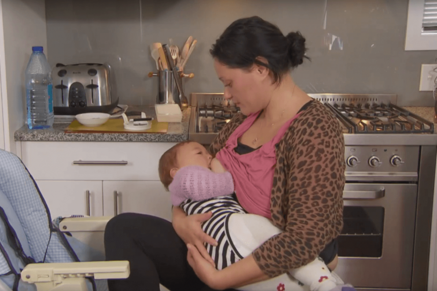 Mother breastfeeding her baby in the kitchen