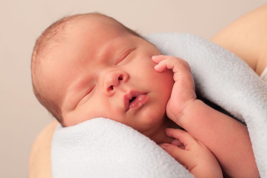 Newborn sleeping baby being held in parent's arms