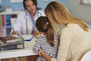 child and their mother at a doctor's clinic talking to a doctor