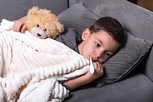 Sick boy with thermometer lying in bed