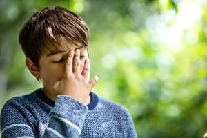 A child outside putting his hand to his head - feeling unwell