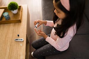 A girl with diabetes using a digital monitor to test her glucose levels